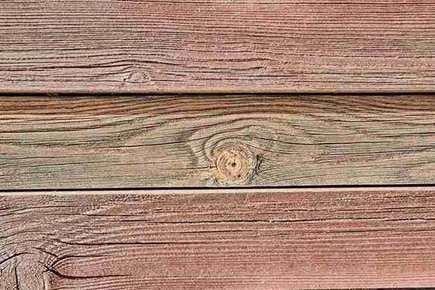 Close-up of weathered cedar boards with visible grain patterns, showing the texture and natural aging of wooden fence materials.