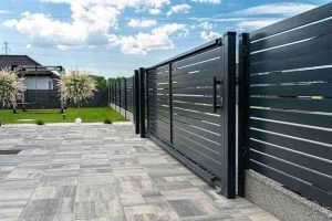 Modern sliding driveway gate with horizontal metal panels installed on a residential property