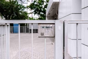 Close-up of an automated gate keypad mounted on a metal fence outside a building